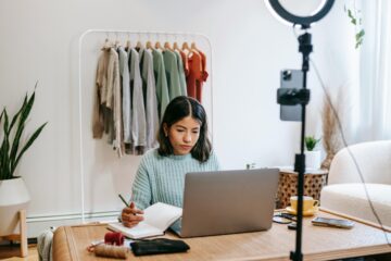 Vrouw achter een laptop maakt aantekeningen als afbeelding bij een blog over